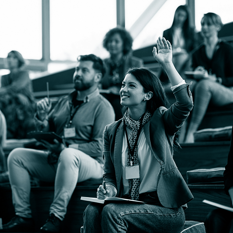 Female entrepreneur raising a hand to ask a question while attending business seminar.